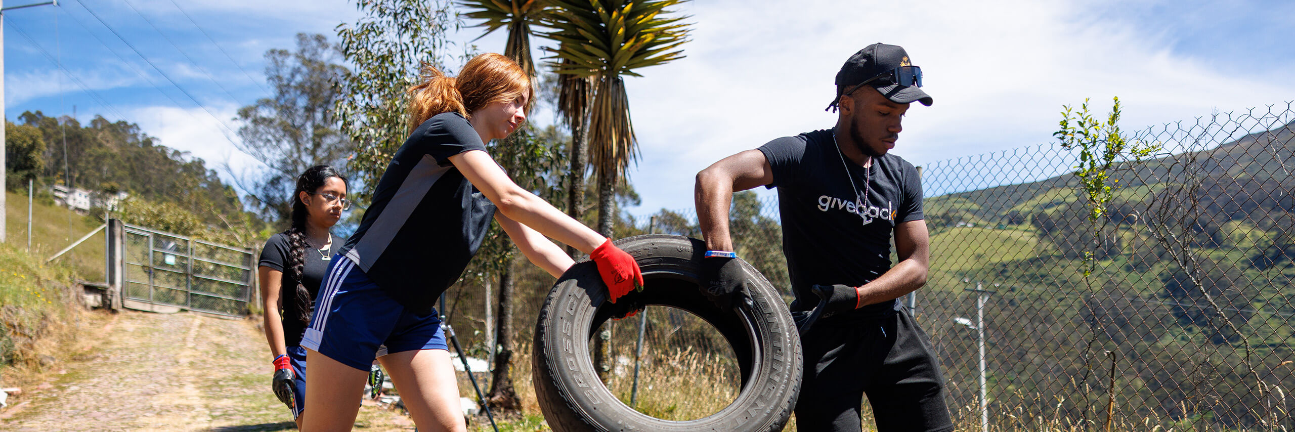 Students pass tires to each other while cleaning up trash.